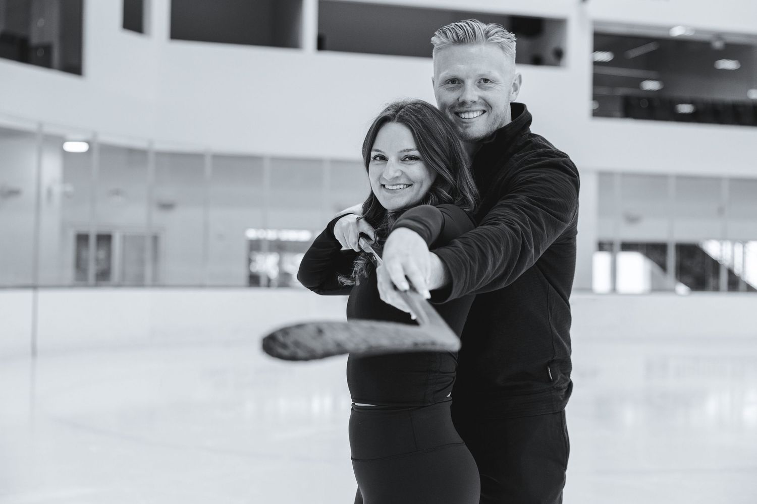very creative shot of couple on ice holding hockey stick up in front of of their faces for engagement shoot in fort lauderdale