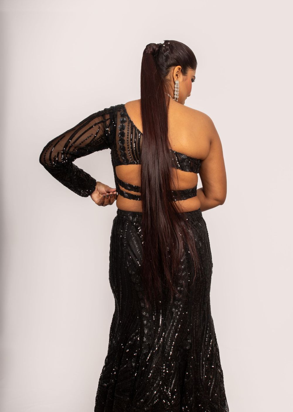 High-fashion pose of a woman wearing a black sequin ethnic outfit.