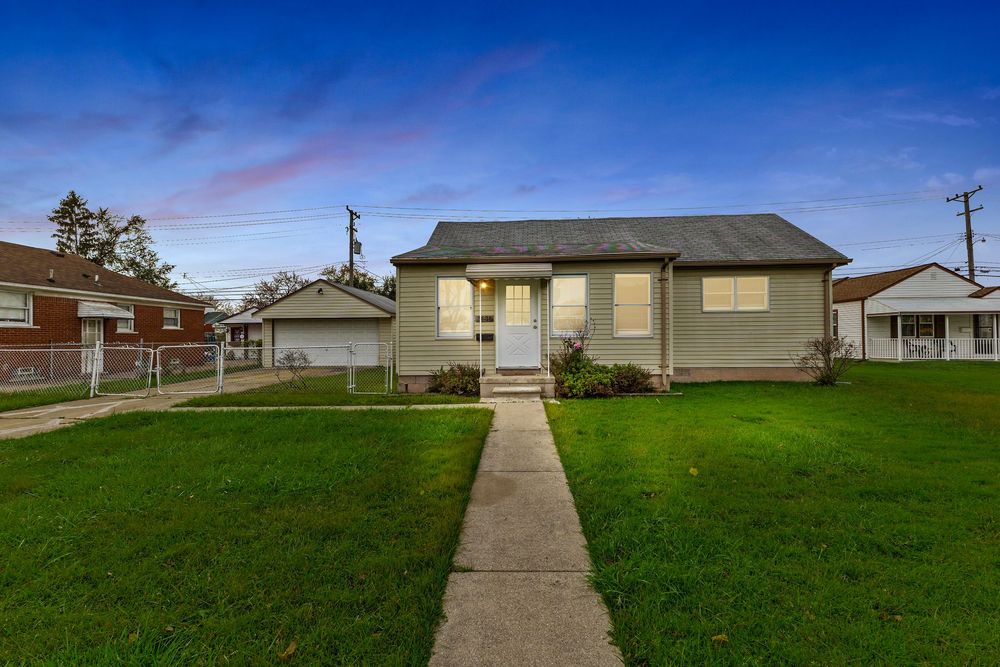 Charming bungalow home at dusk with green lawn, concrete walkway, and attached front entry.