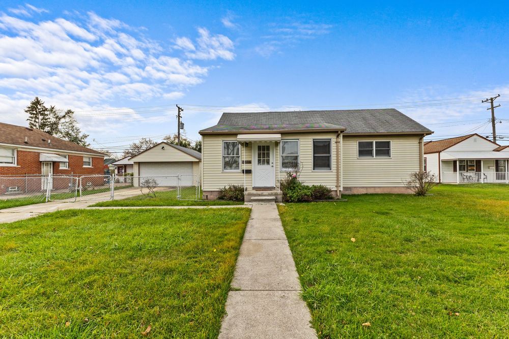 Single-story bungalow with green lawn, concrete front walkway, gray siding, and attached neighbors on a sunny day.