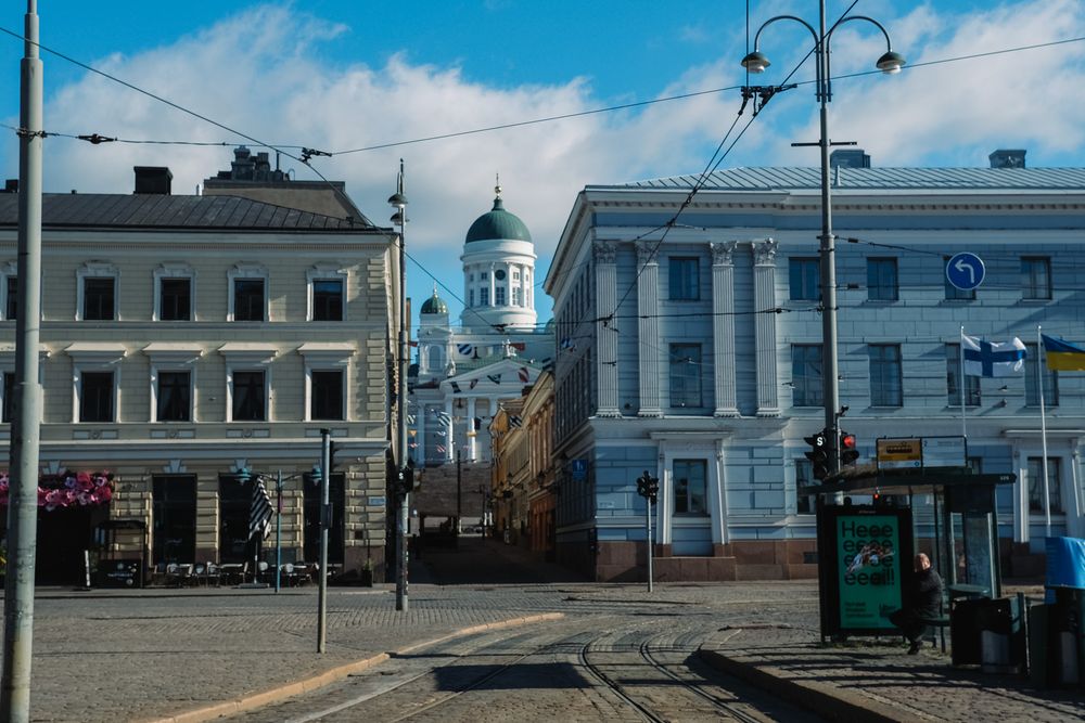 Helsinki city street with tram tracks leads toward the iconic white Helsinki Cathedral dome in the background.