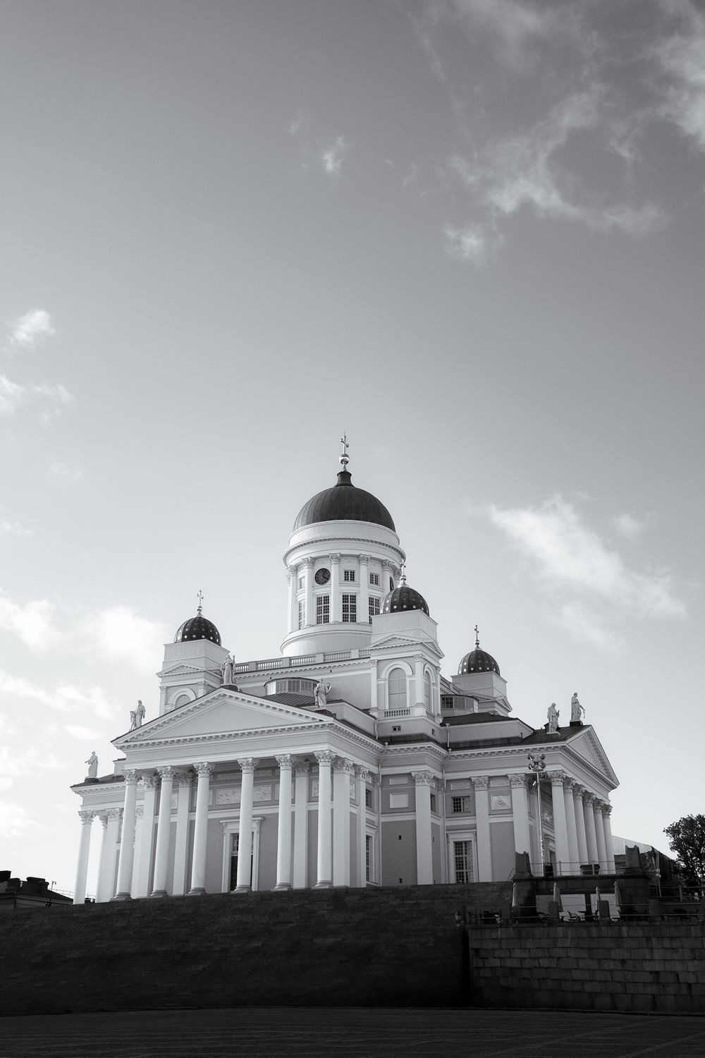 Black and white photo of Helsinki Cathedral with grand columns and domed roof against a cloudy sky.