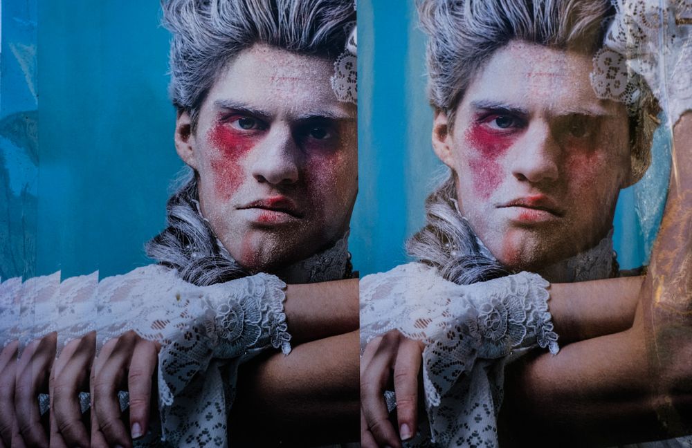 A dramatic theatrical mannequin with rosy cheeks and tousled hair displayed twice in a mirrored artistic composition.
