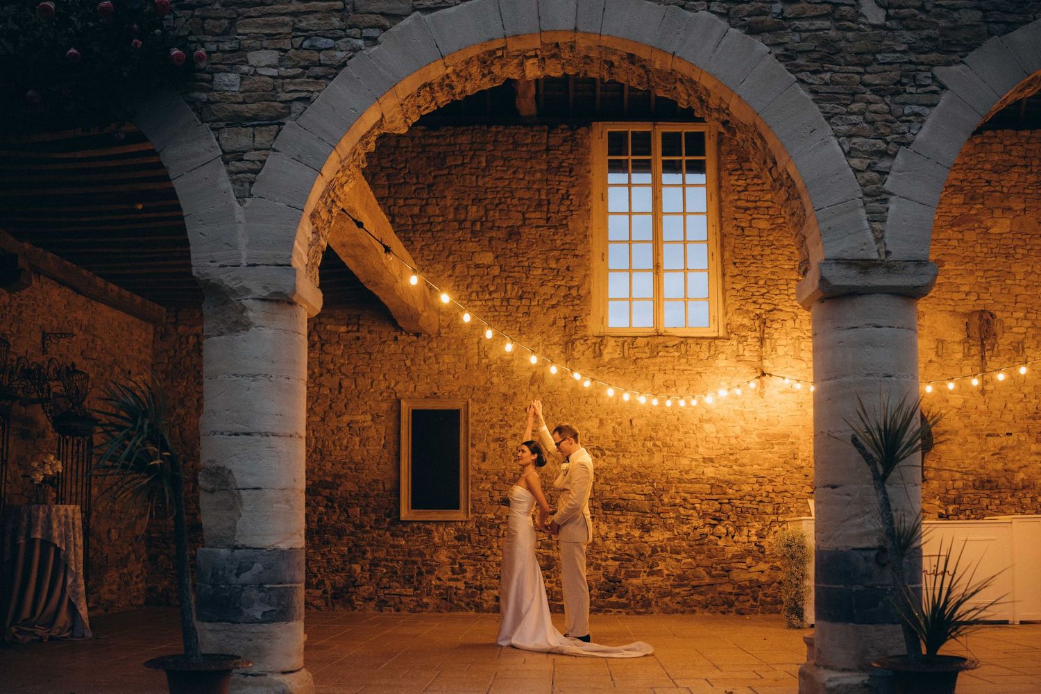 A romantic black and white wedding photograph showing a tender embrace in a natural outdoor setting.