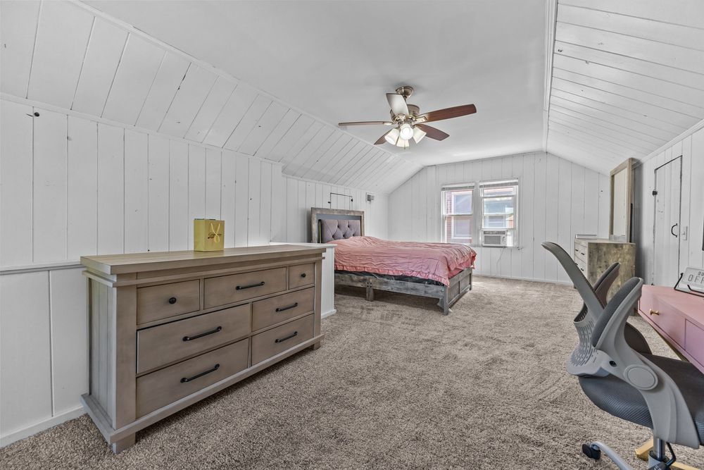 Upper bedroom with vaulted ceiling and white wood panel walls in Dearborn Michigan bungalow
