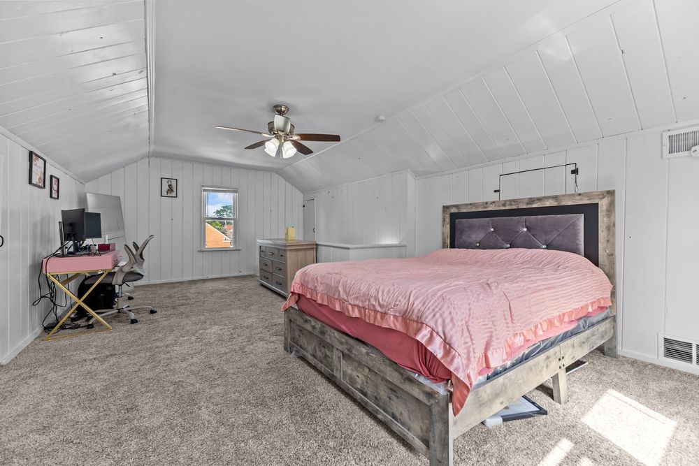 Upper bedroom with vaulted ceiling and white wood panel walls in Dearborn Michigan bungalow