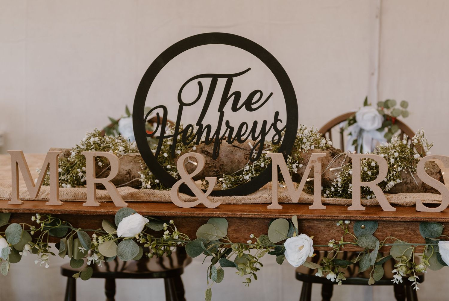 Rustic wedding sweetheart table with MR & MRS signs, The Henreys family name sign, and eucalyptus floral garland.