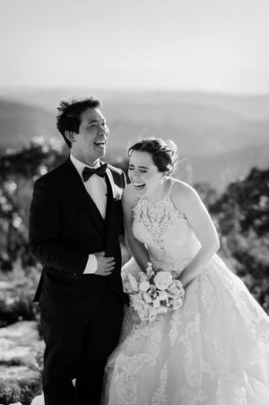 Laughing bride and groom in black and white wedding portrait with mountain valley backdrop.
