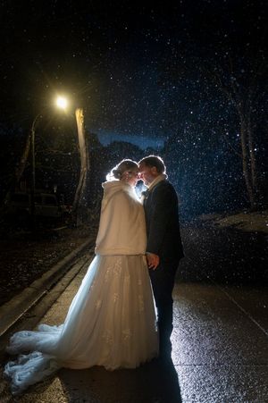 Bride and groom share a romantic moment in the snow at night, illuminated by a street lamp on their wedding day.