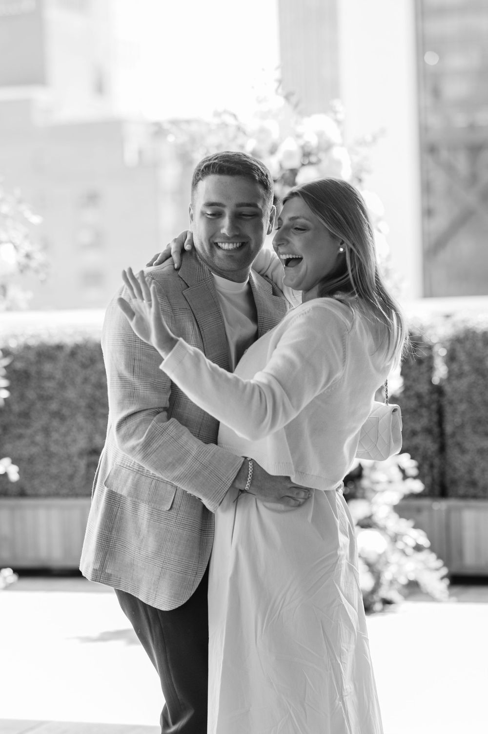Happy couple embracing and laughing together on a sunny rooftop in a black and white photo.