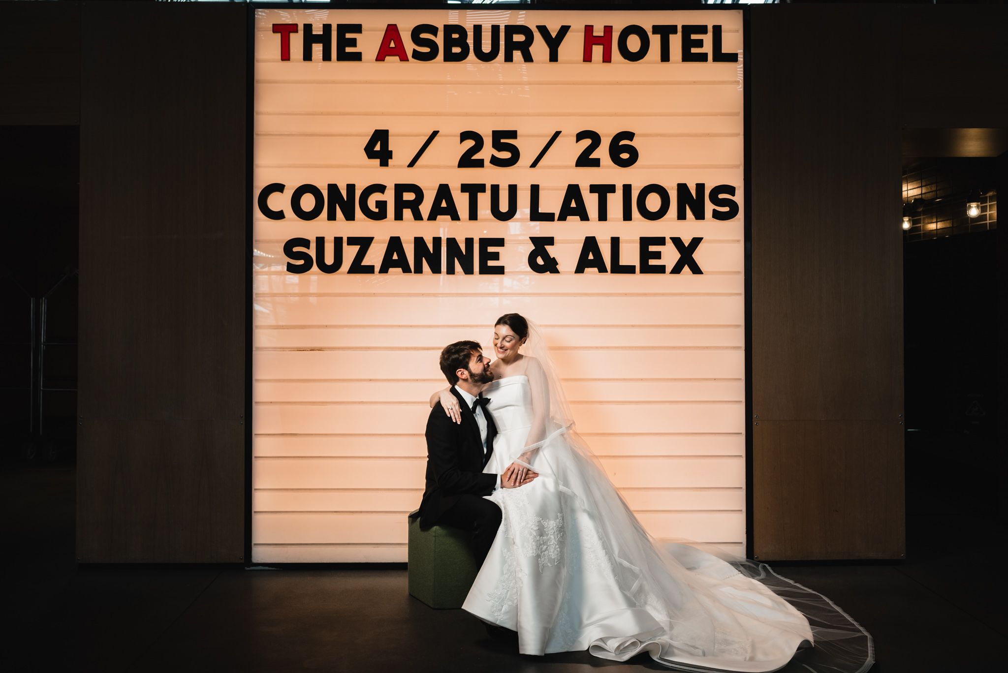 Bride and groom pose before Asbury Hotel marquee sign congratulating Suzanne and Alex on April 25, 2026.