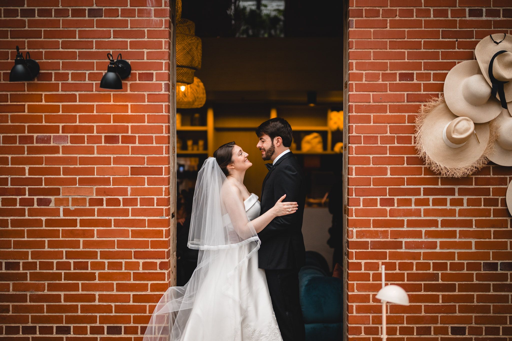 Bride and groom share a tender moment in a brick archway doorway during outdoor wedding portraits.