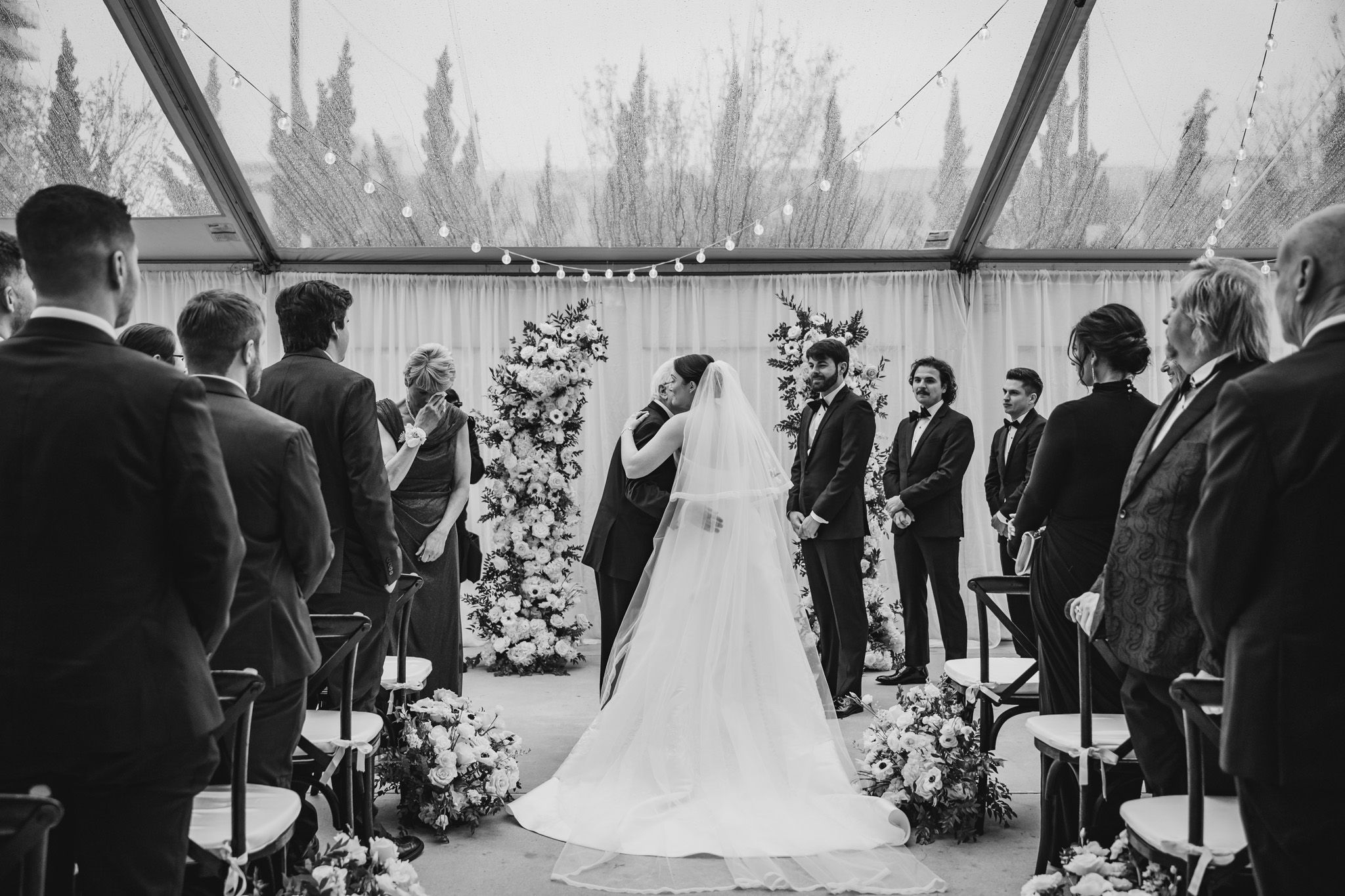 Black and white photo of bride and groom at the altar during an elegant outdoor wedding ceremony.