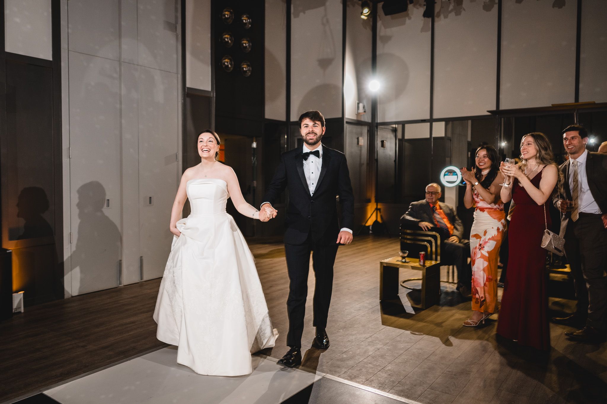 Bride and groom make grand entrance at their wedding reception at The Asbury Hotel, greeted by cheering guests.