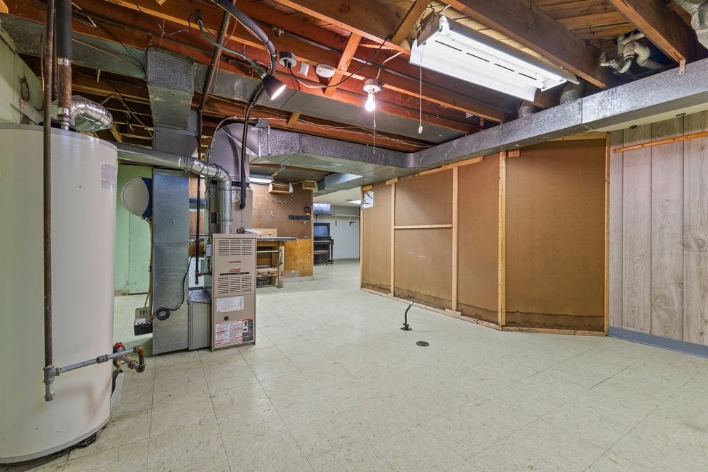 Unfinished basement with exposed ceiling joists, water heater, furnace, and open concrete floor space.