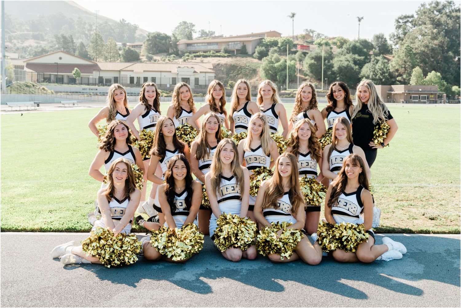 SLO High varsity dance team posing with gold poms at Holt Stadium during morning team photos, celebrating the return of dance after 5 years.