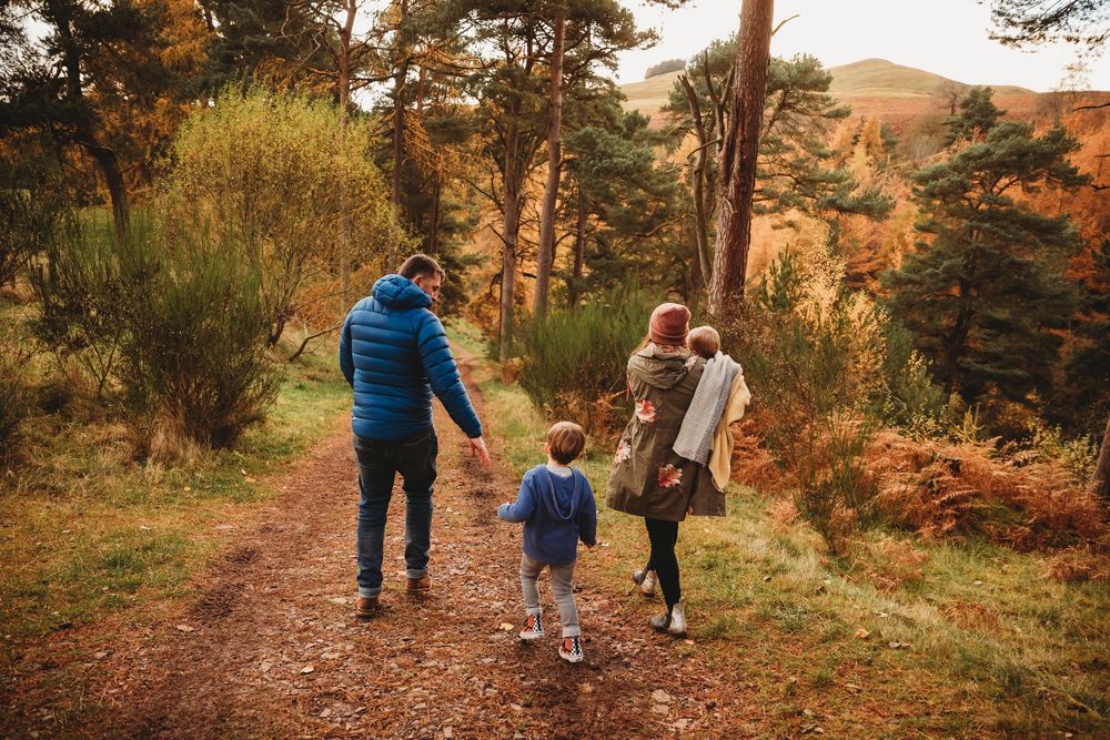 Family hiking on an autumn forest trail, surrounded by colorful fall foliage and scenic mountain views.