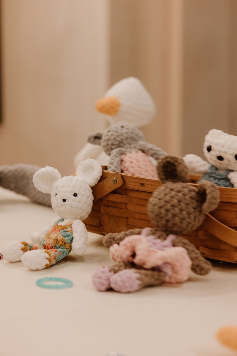 Handmade crochet stuffed animals including a white mouse and brown bears arranged in and around a wicker basket.