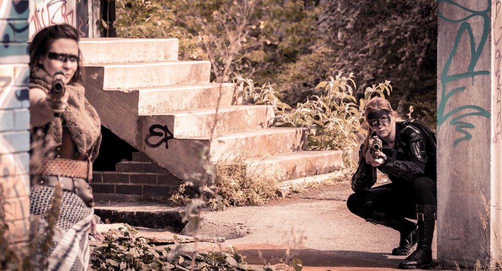 Two people posing dramatically near graffiti-covered stairs in an urban abandoned setting.