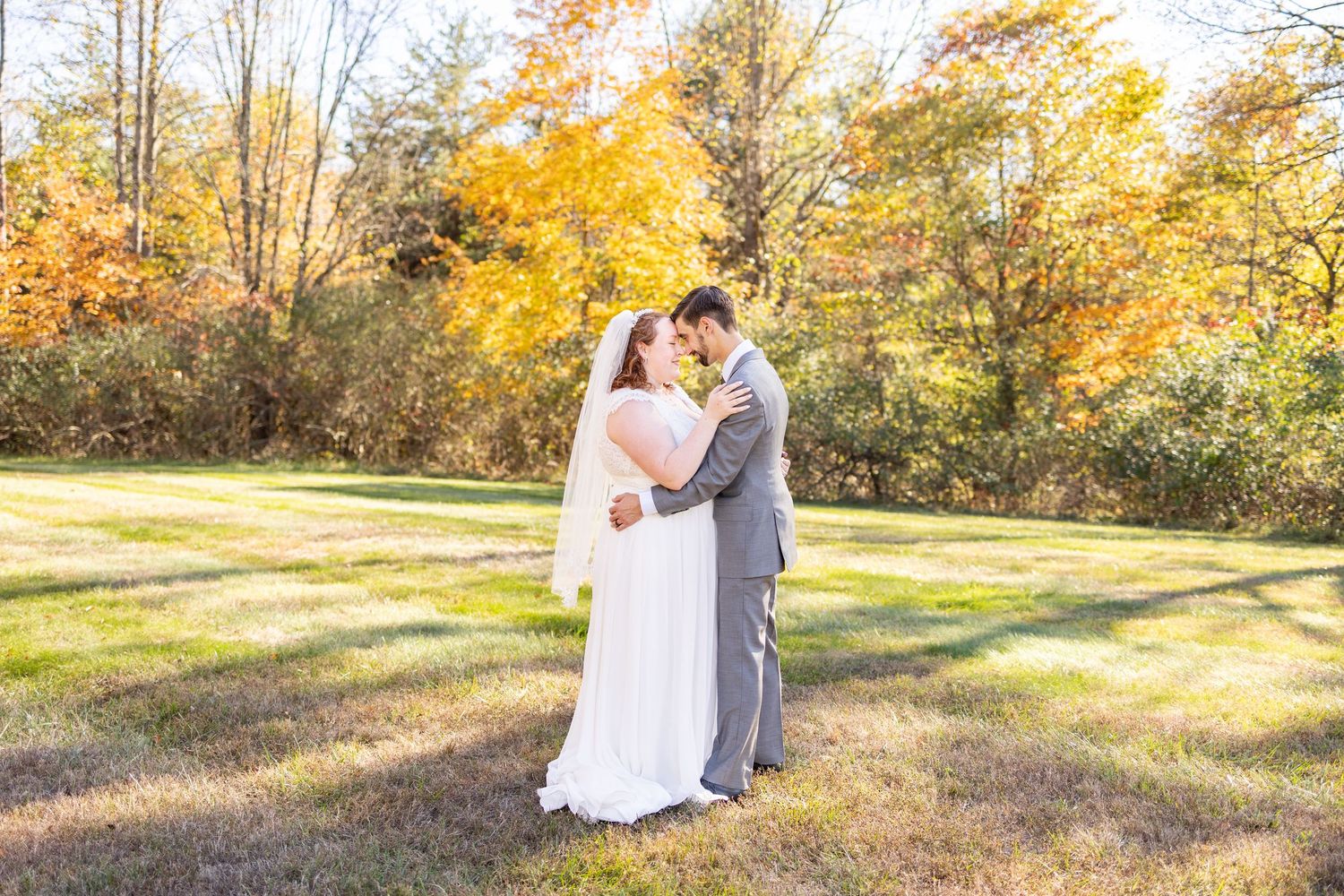 Bride and groom share a romantic moment in a sunlit autumn meadow surrounded by vibrant fall foliage. Hocking Hills Elopememt