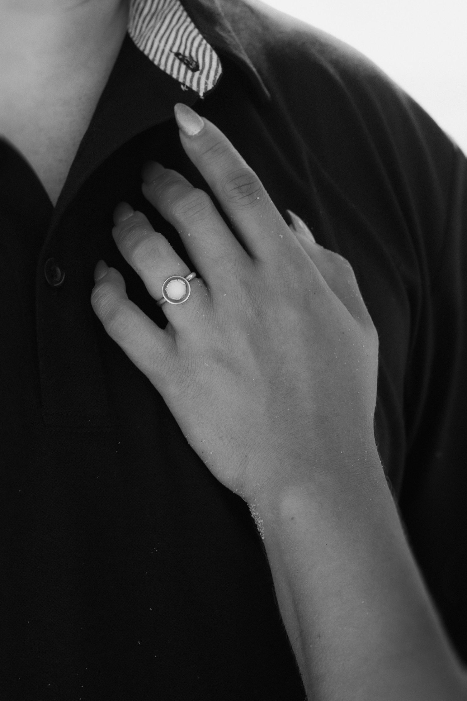Womans hand showcasing ring in Pompano Beach Pier during engagement couples session.
