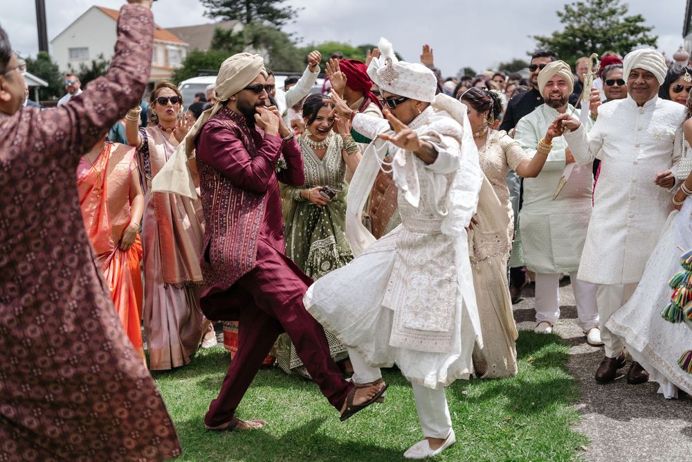 Joyful Indian wedding guests dancing outdoors in vibrant traditional attire, celebrating with lively Baraat procession.