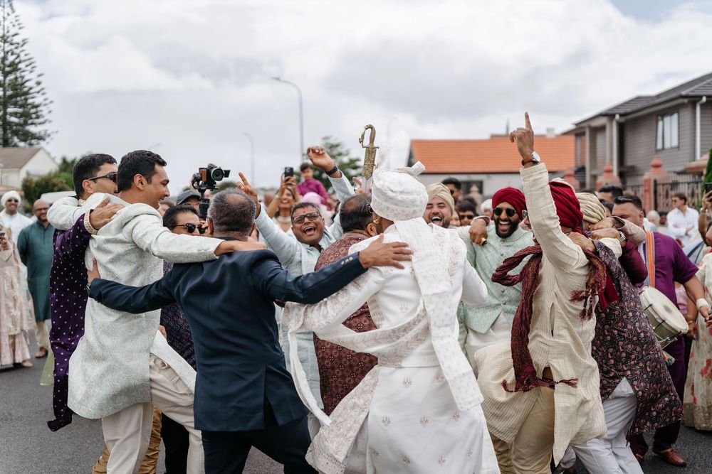 Joyful Indian wedding celebration with guests dancing in traditional attire on a suburban street.