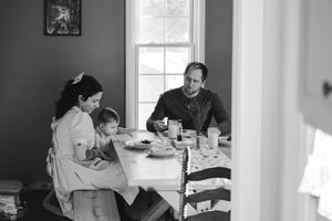 A mother and father sit at the table eating breakfast