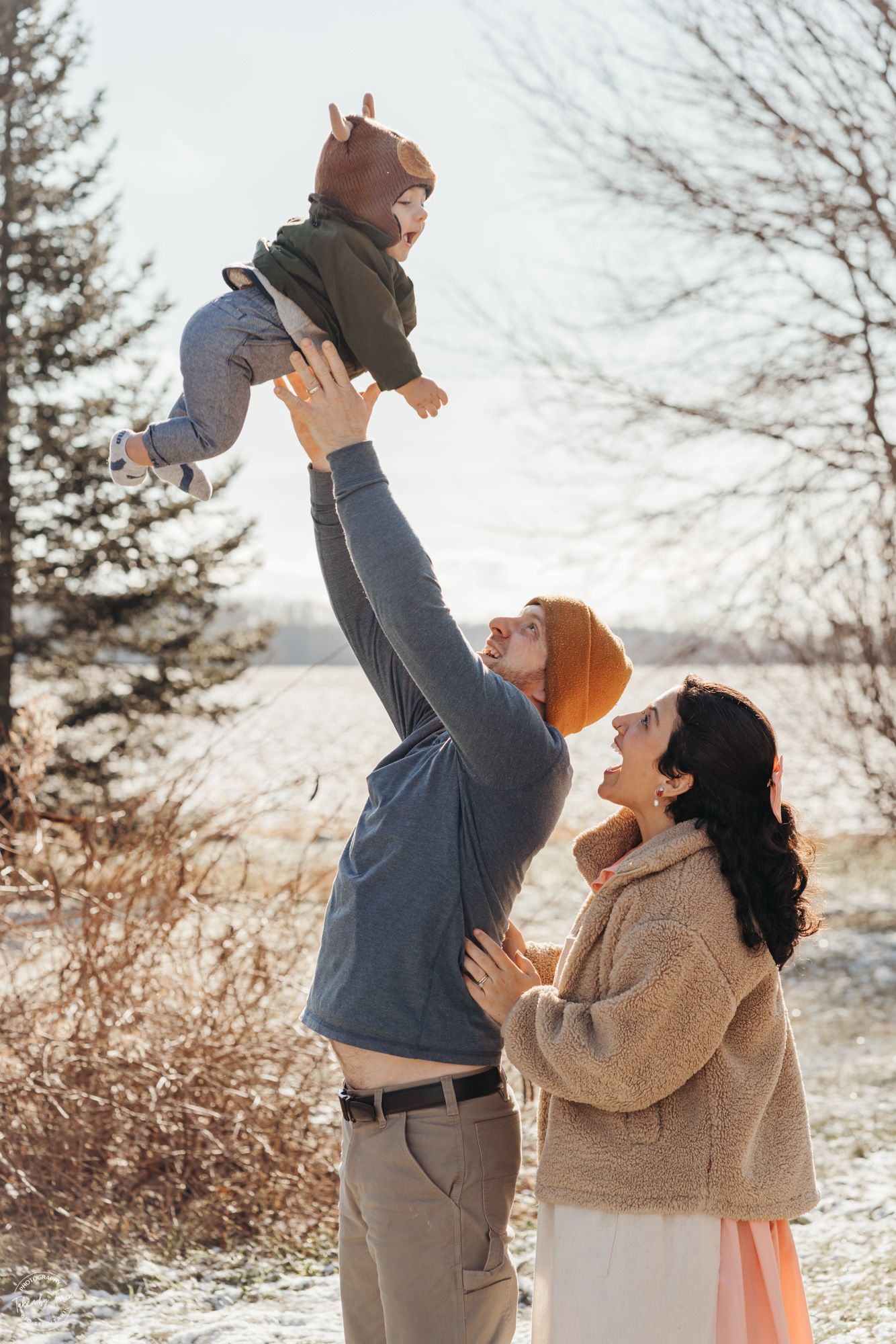 A mother and father play with their son in the winter air