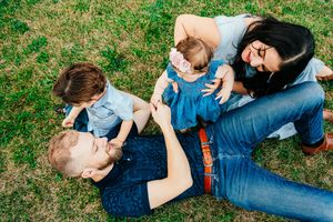 A photo of a family of 4 giggling on the ground