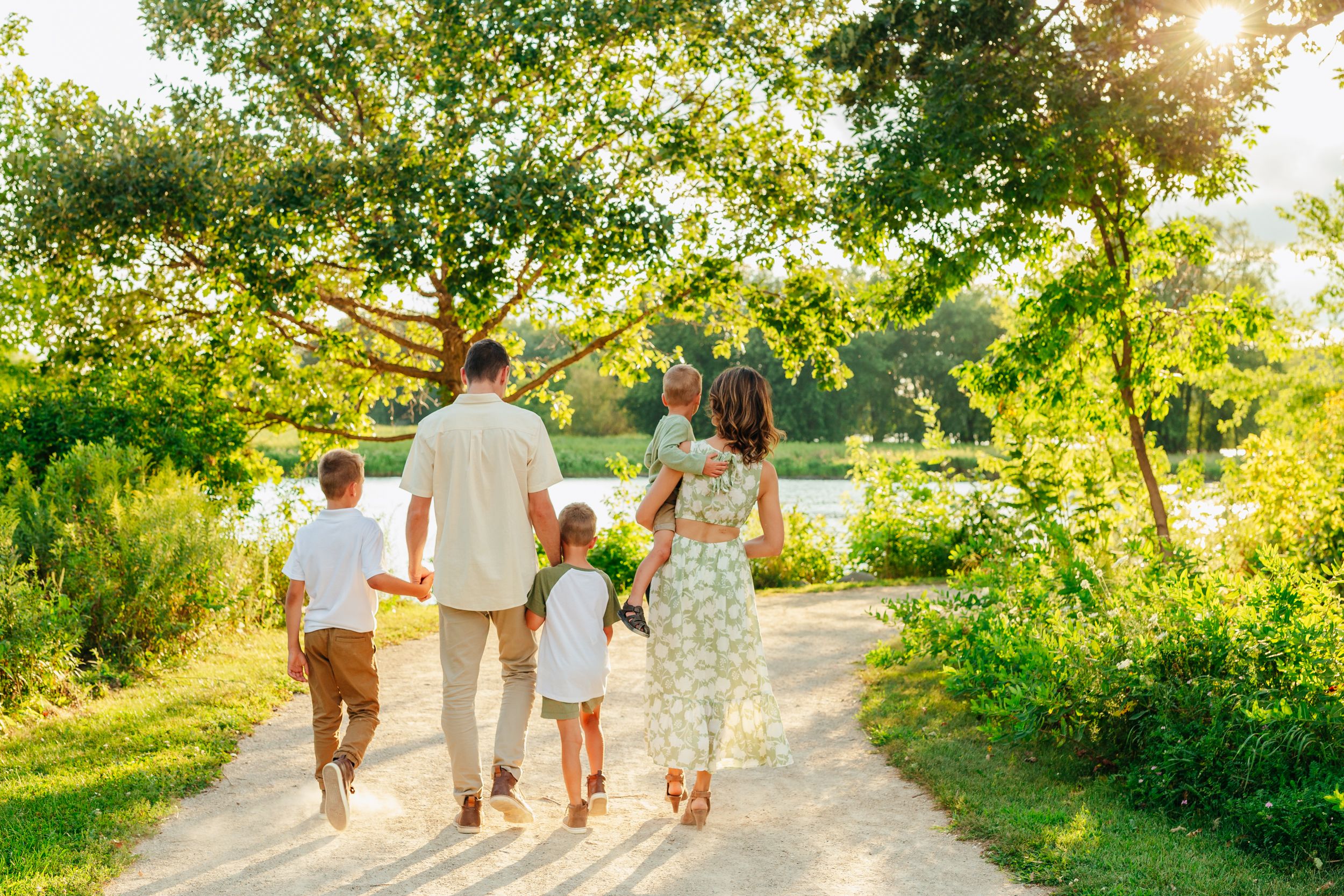 A photo of a family of five walking away from the camera in a green scenery