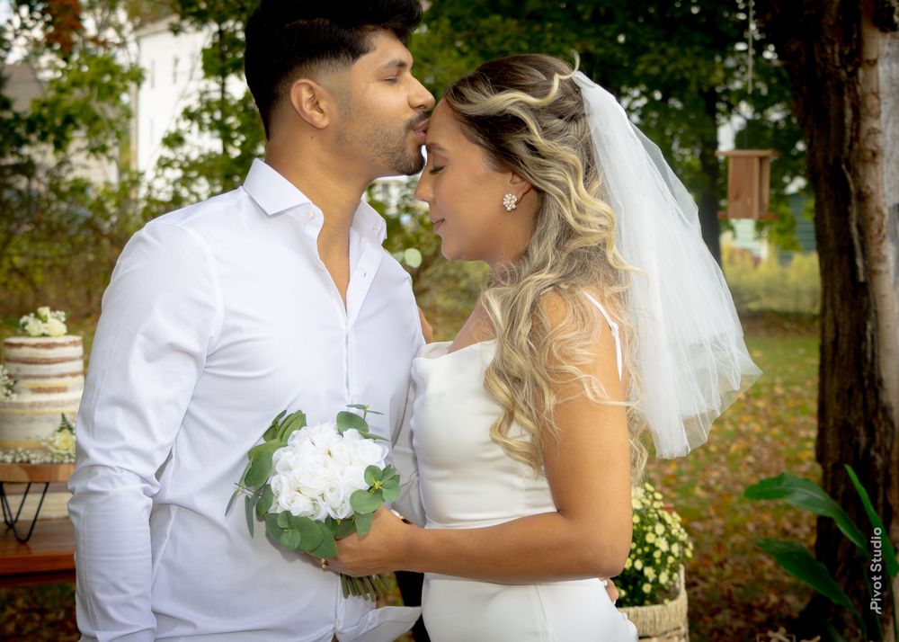 Bride and groom share a tender kiss holding white hydrangea bouquet at an outdoor garden wedding.