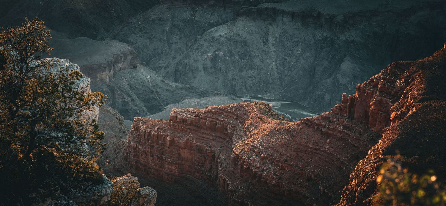 Panoramic sunset view over the Grand Canyon with silhouetted rock formations and warm twilight sky.