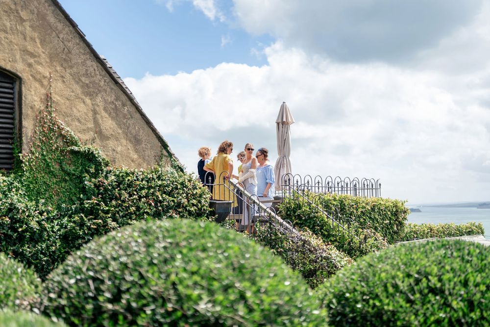Group of guests gathered on a terraced garden stairway overlooking a scenic coastal view with manicured hedges.