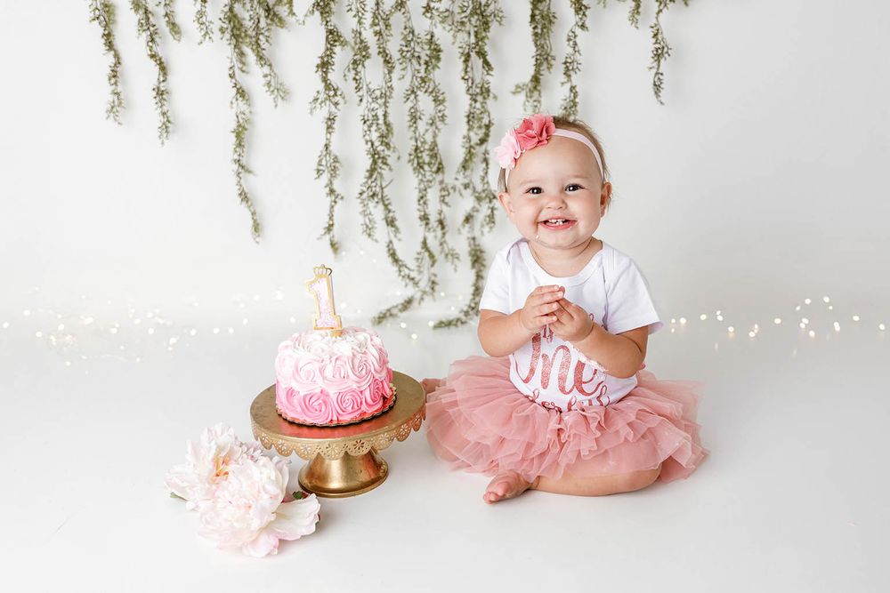 Smiling baby girl in pink tutu enjoys first birthday cake smash photo session by Temescal Valley cake smash photographer.