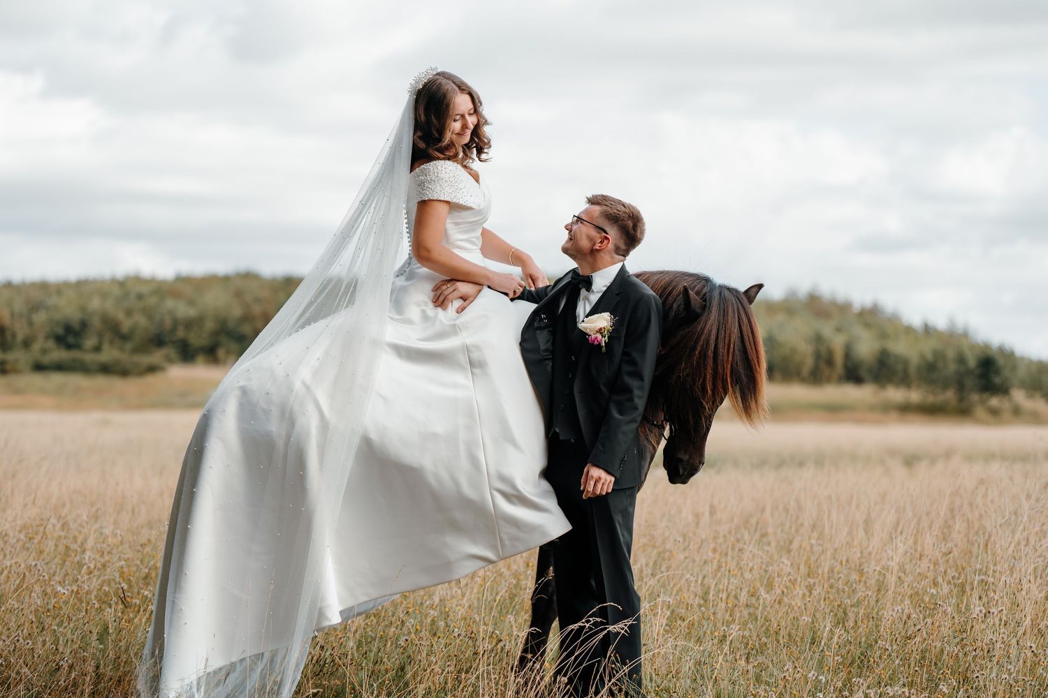 Bride on her islandic horse smiling and looking down at her groom.