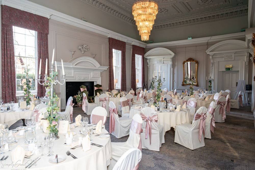 The Cloisters wedding ceremony room setup at Coombe Abbey featuring a grand chandelier and pink bows.