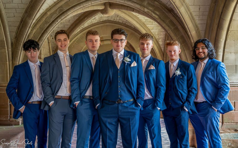 SimplyGreatShots capturing groom Mark and groomsmen in navy suits under a stone archway at Coombe Abbey.