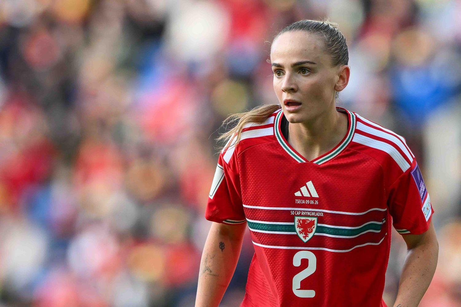 Female soccer player in red Wales jersey number 2 on field during match.