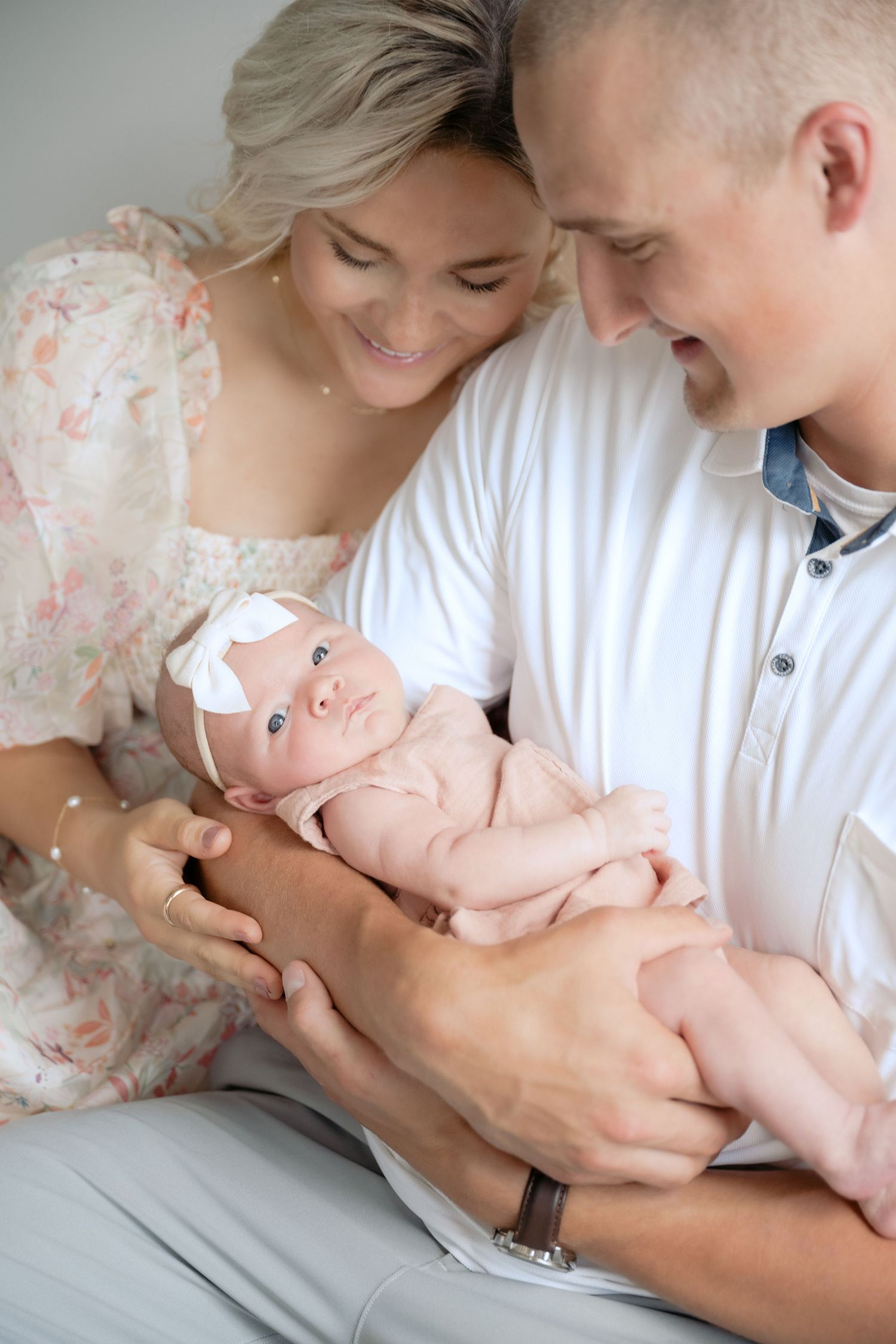 parents admiring newborn baby in their arms while baby looks at camera during in-studio lifestyle newborn session in stillwater, mn