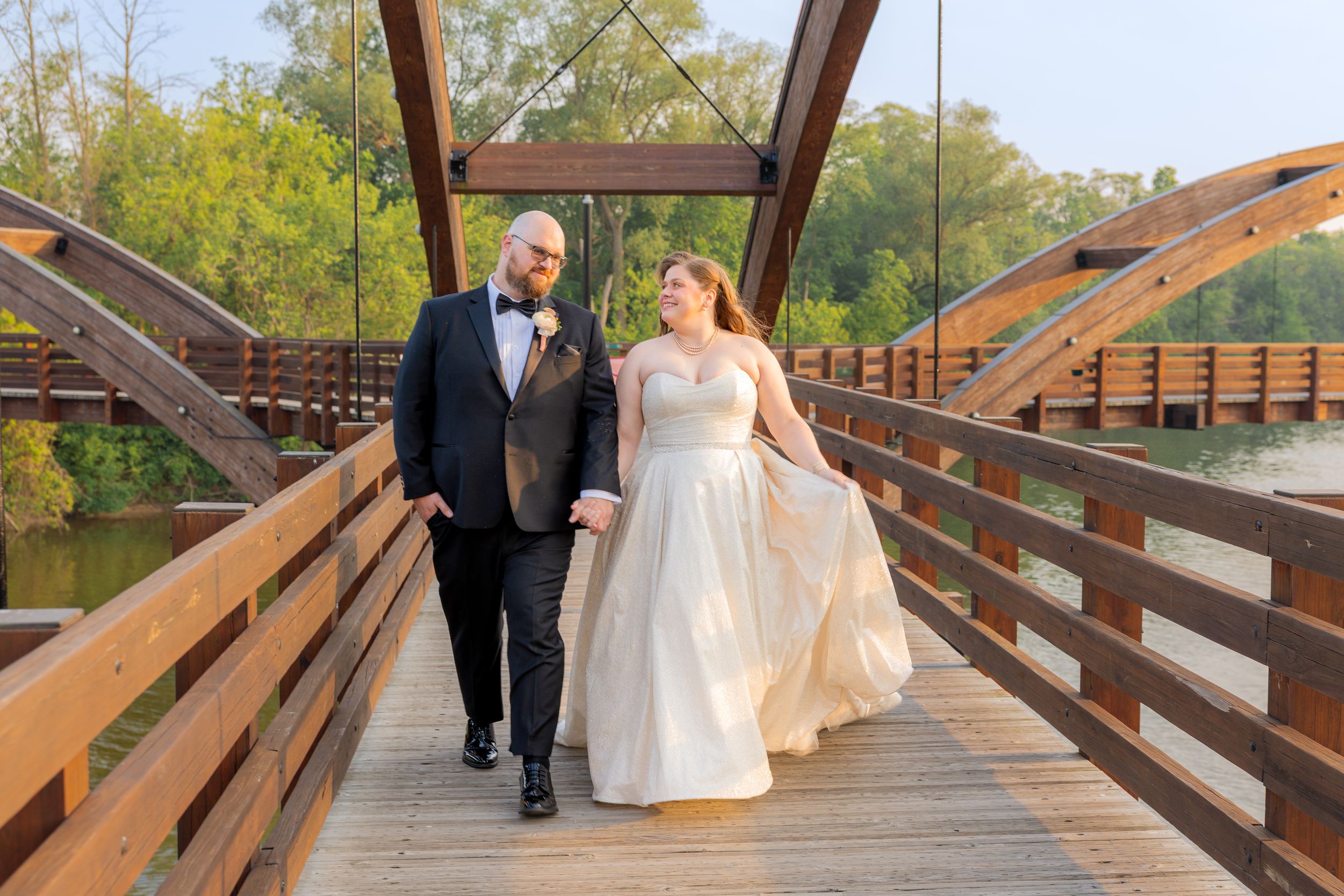 Bride and Groom walking and looking at each other on bridge by South Florida wedding photographer