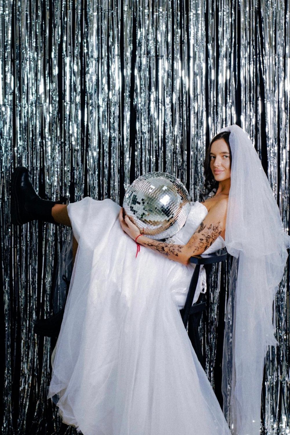 Bride holding oversized disco ball at trendy wedding reception styled with luxury décor, romantic lighting, and upscale aesthetic decoration