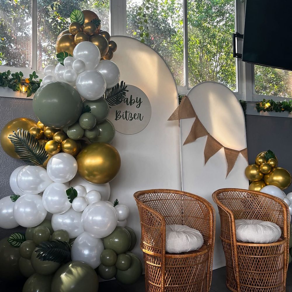 Wild One baby shower party balloon backdrop with green and gold balloon arch styled for luxury safari celebration décor setup