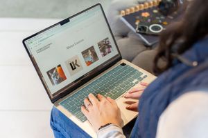 Woman browsing an e-commerce website on a modern laptop while sitting on a couch at home.