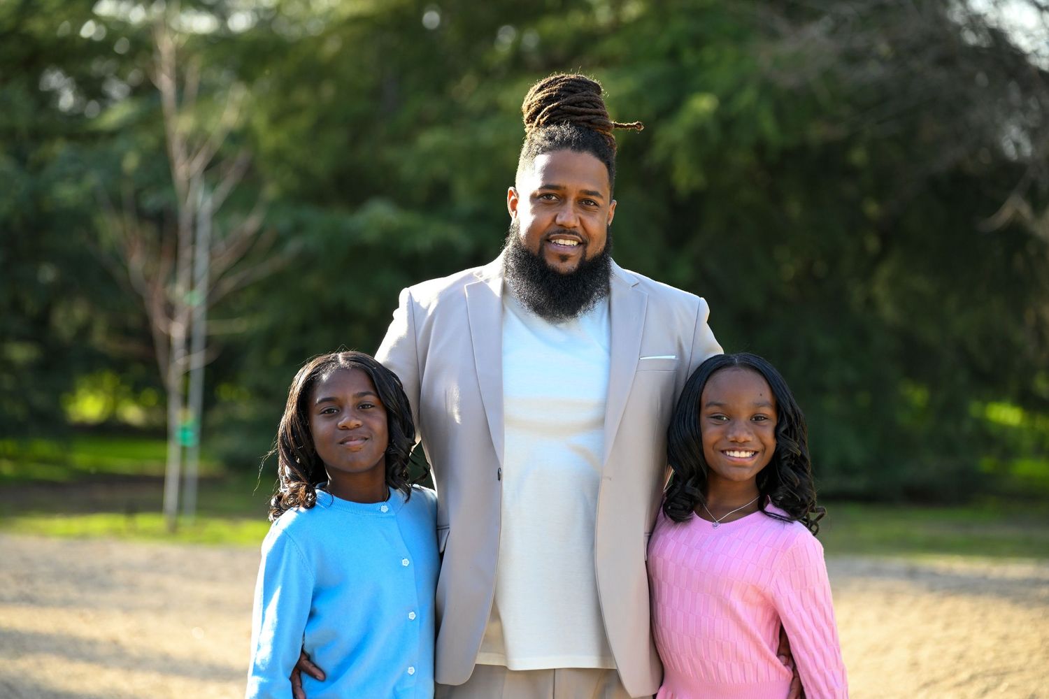 Family group posing together for outdoor portraits in coordinated pastel outfits.