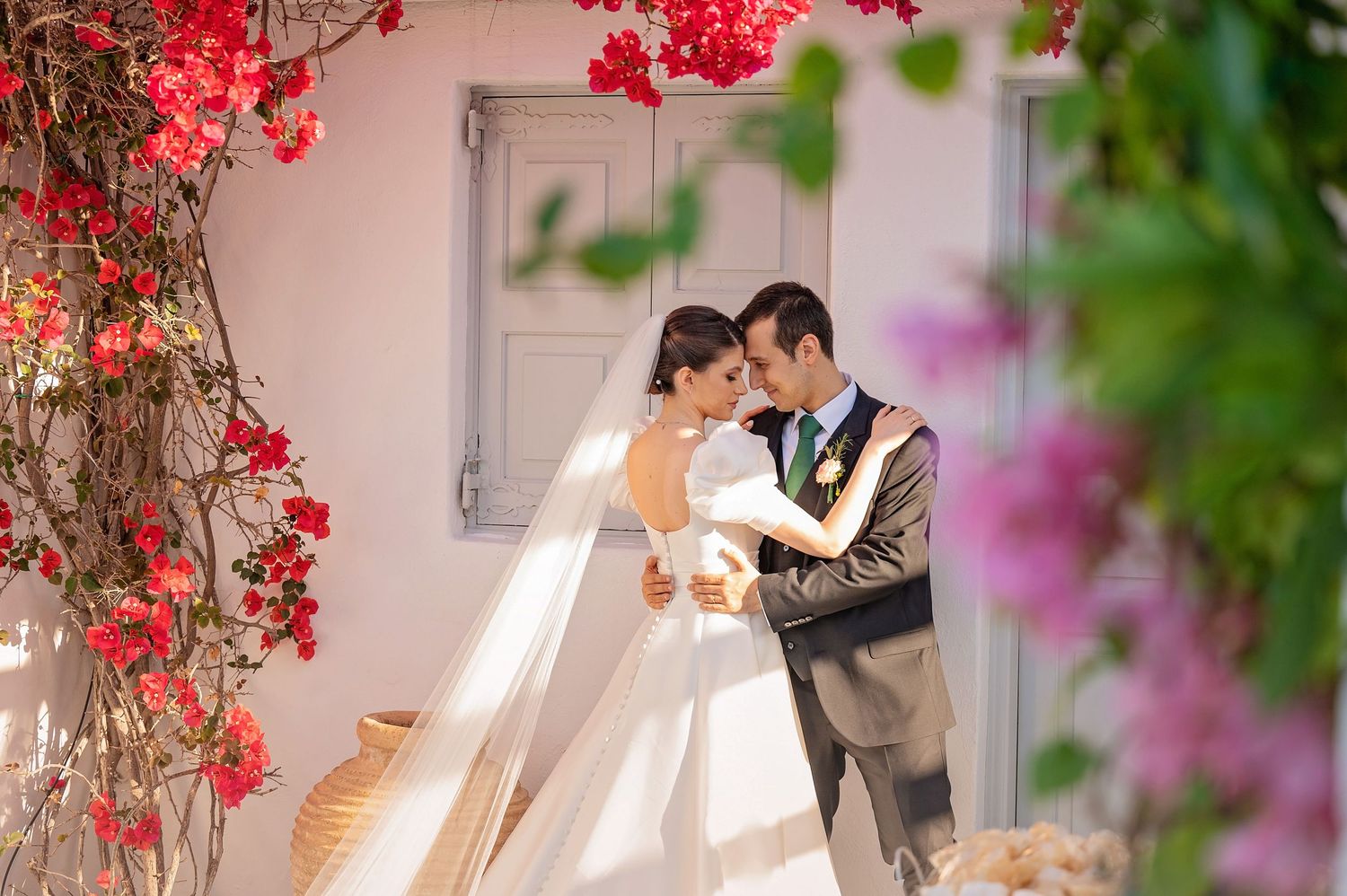 A romantic wedding moment amidst blooming red flowers and greenery.