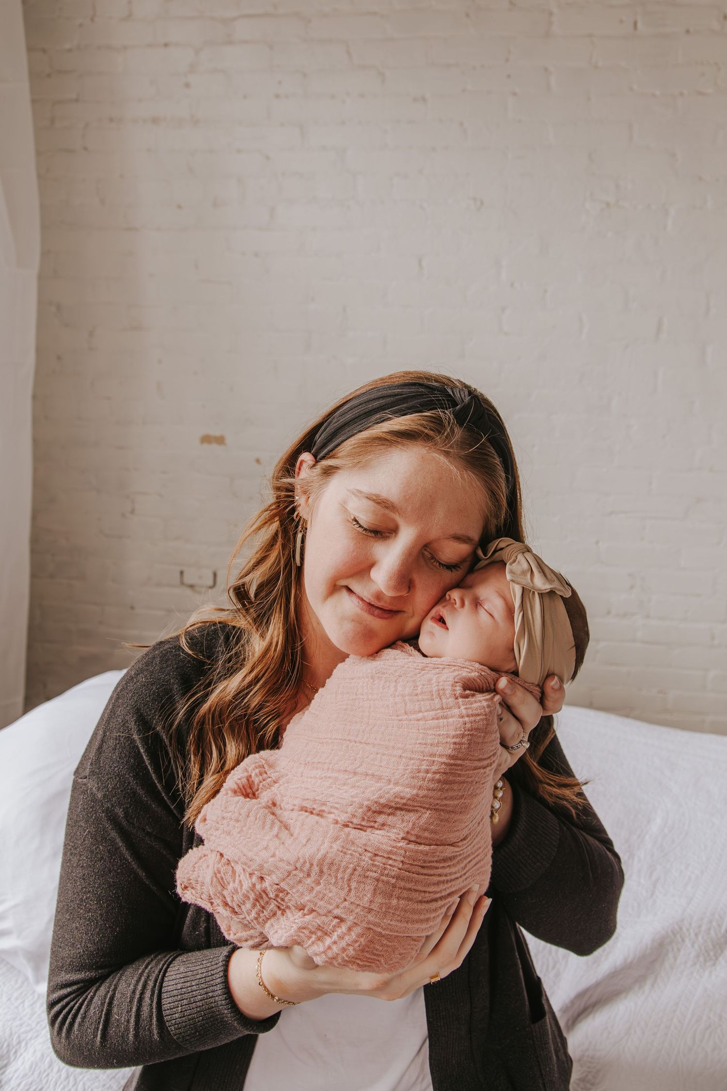 Intimate indoor portrait series showing tender moments with a swaddled baby.