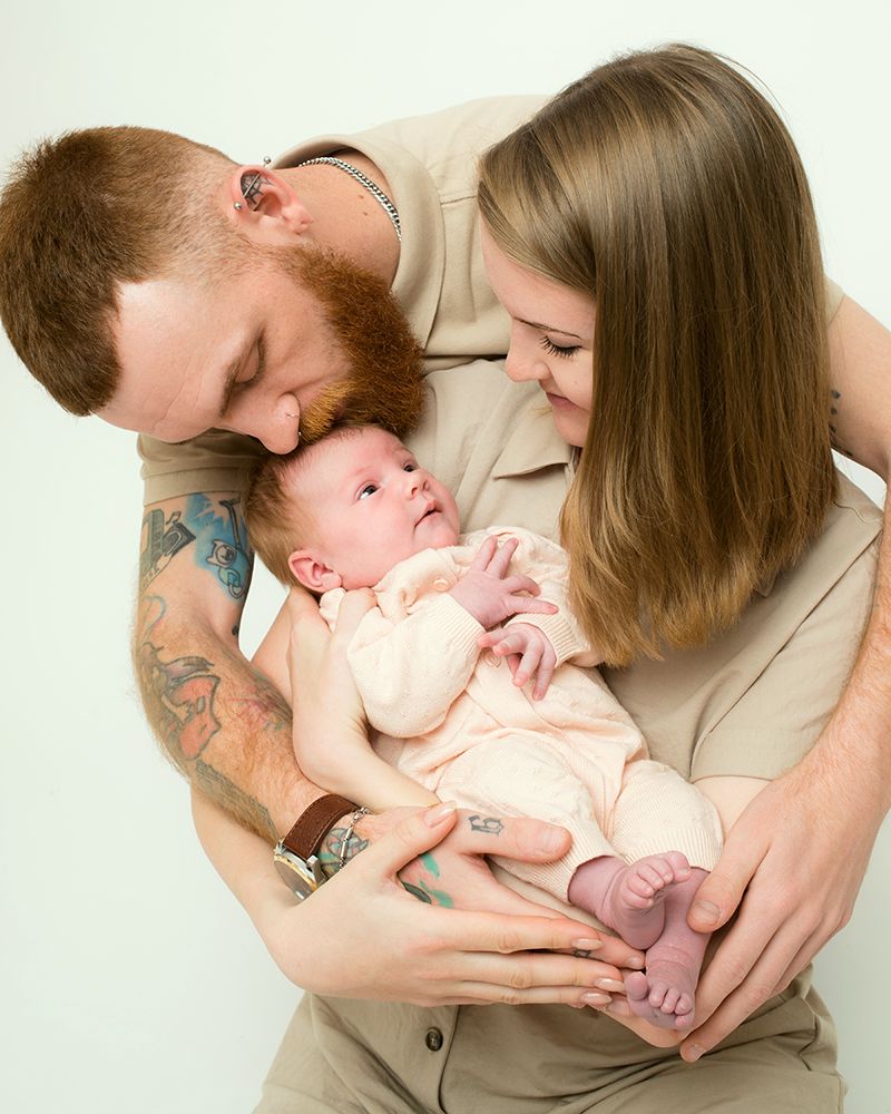 A man and woman cradle their baby together, highlighting a precious family bond in this newborn photo by Abigail's Studio.