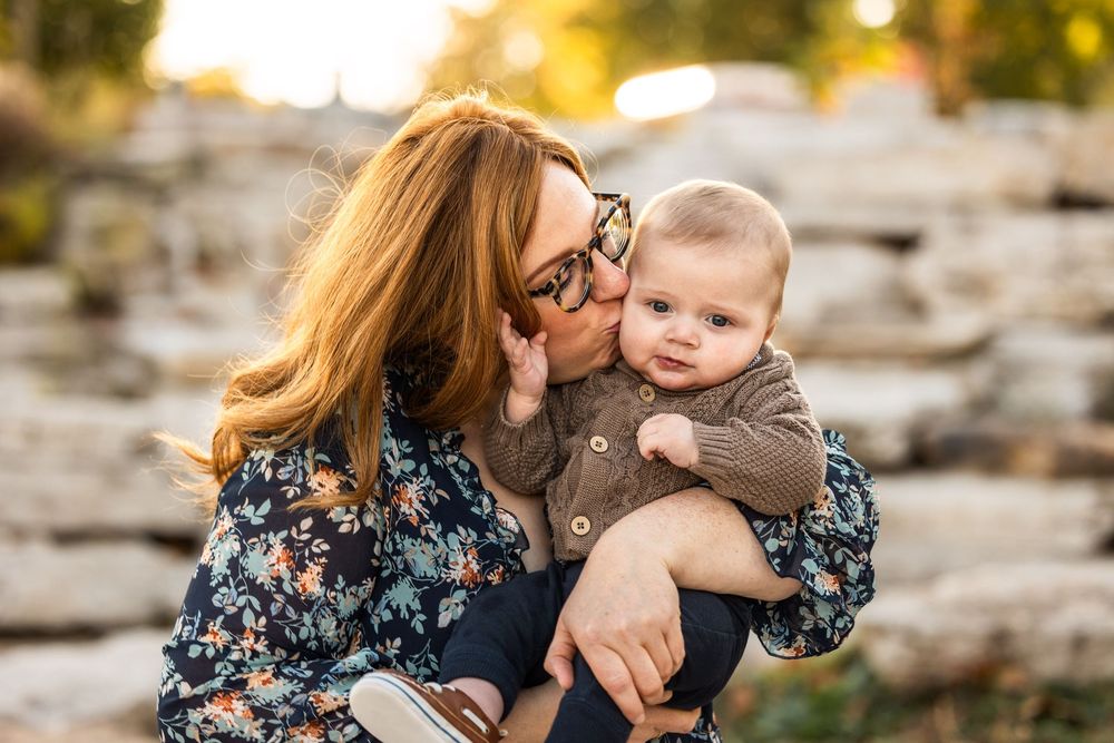 Parent and baby sharing tender moment during outdoor sunset photo session.