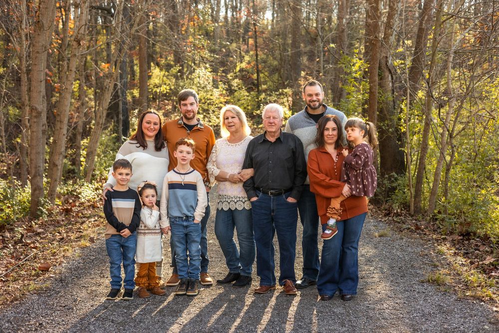 Extended family group portrait on wooded path during fall season.